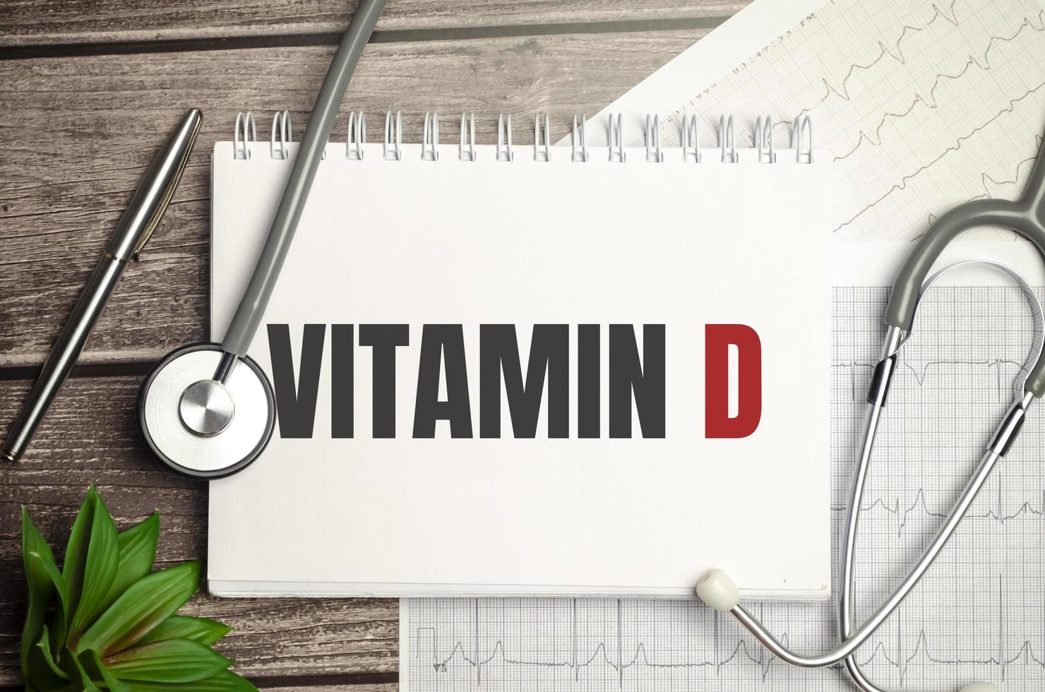 Text VITAMIN D on notebook with stethoscope and pen on wooden background photo