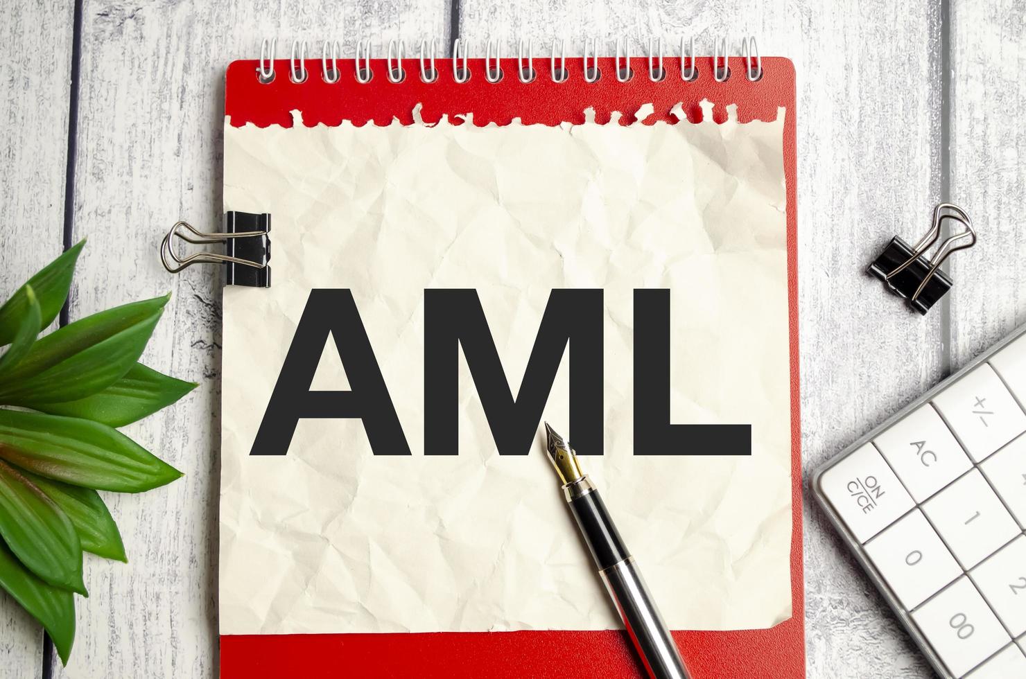 AML Anti-Money Laundering words on notepad and pen on wooden background photo