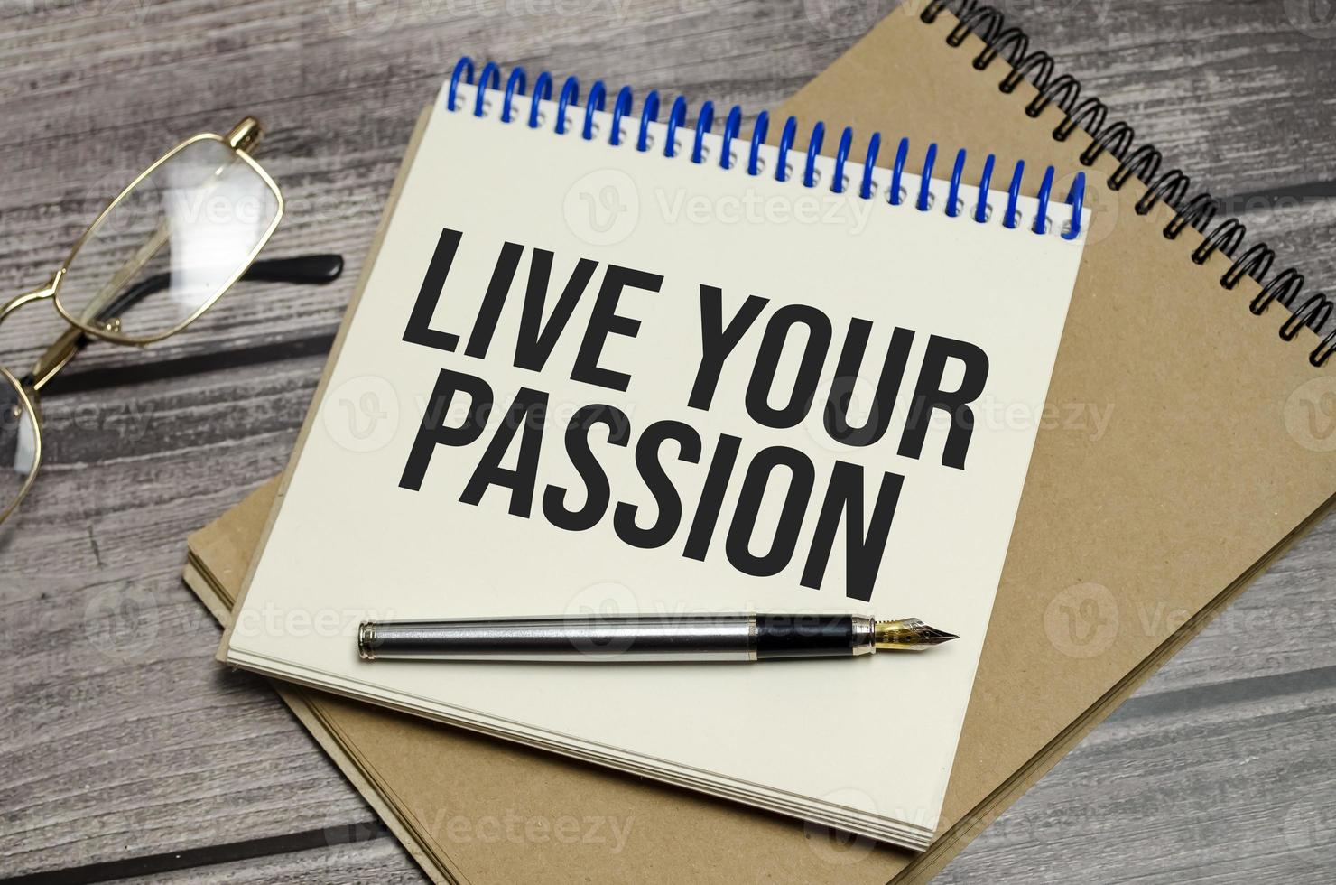 LIVE YOUR PASSION text on notepad and pen on wooden background photo