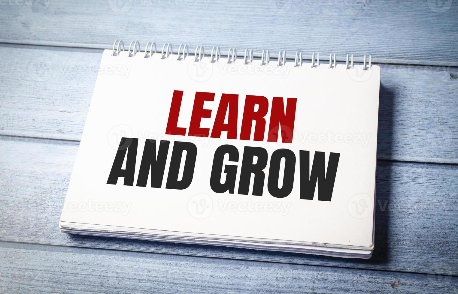 Learn and grow symbol on notepad and blue wooden background photo