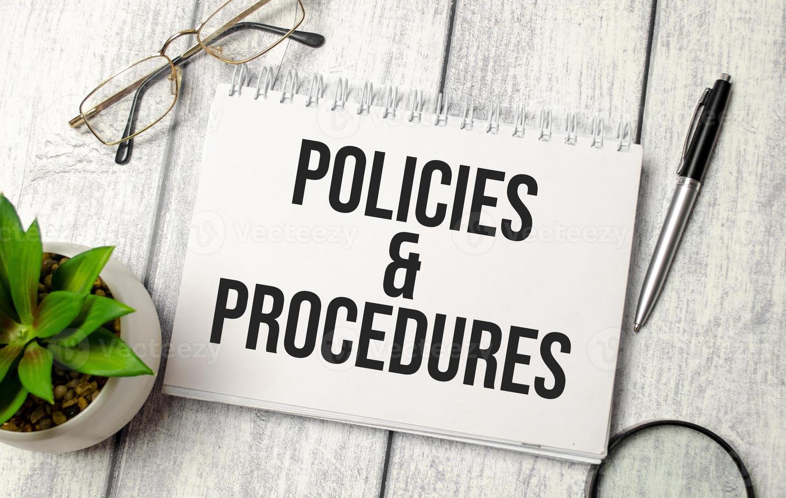 texto de políticas y procedimientos en el bloc de notas con gafas, bolígrafo y calculadora foto