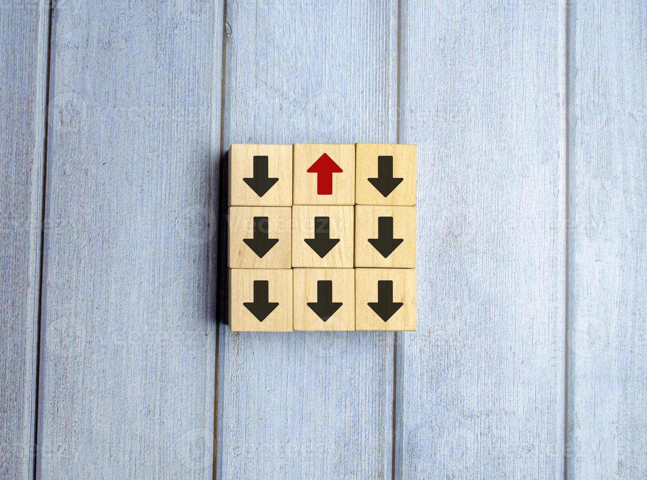 Wooden block with red arrow facing the opposite direction black arrows photo