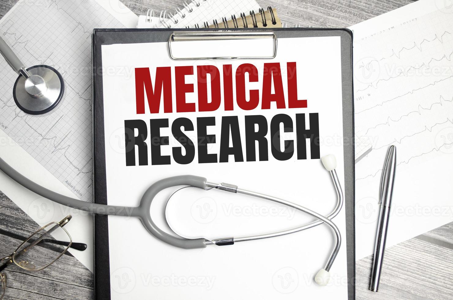 Stethoscope, pens and note with text MEDICAL RESEARCH photo