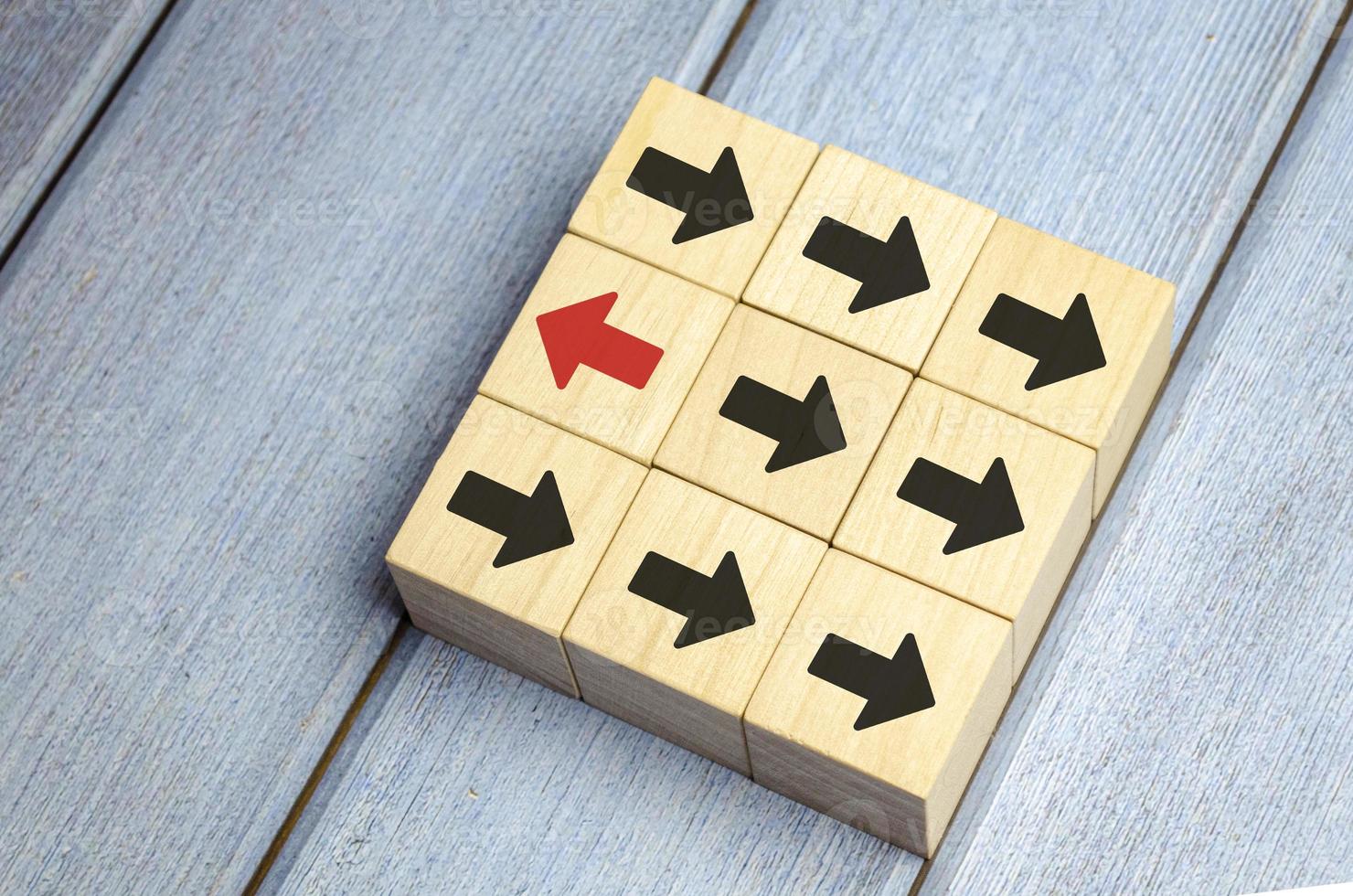 Wooden block with red arrow facing the opposite direction black arrows photo