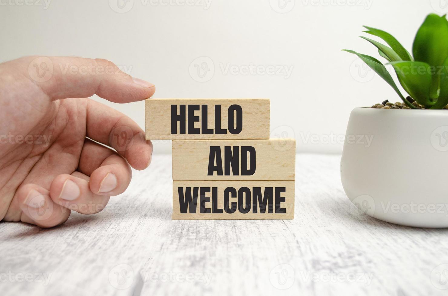 Hello and welcome symbol. Concept words Hello and welcome on wooden blocks. Businessman hand. photo