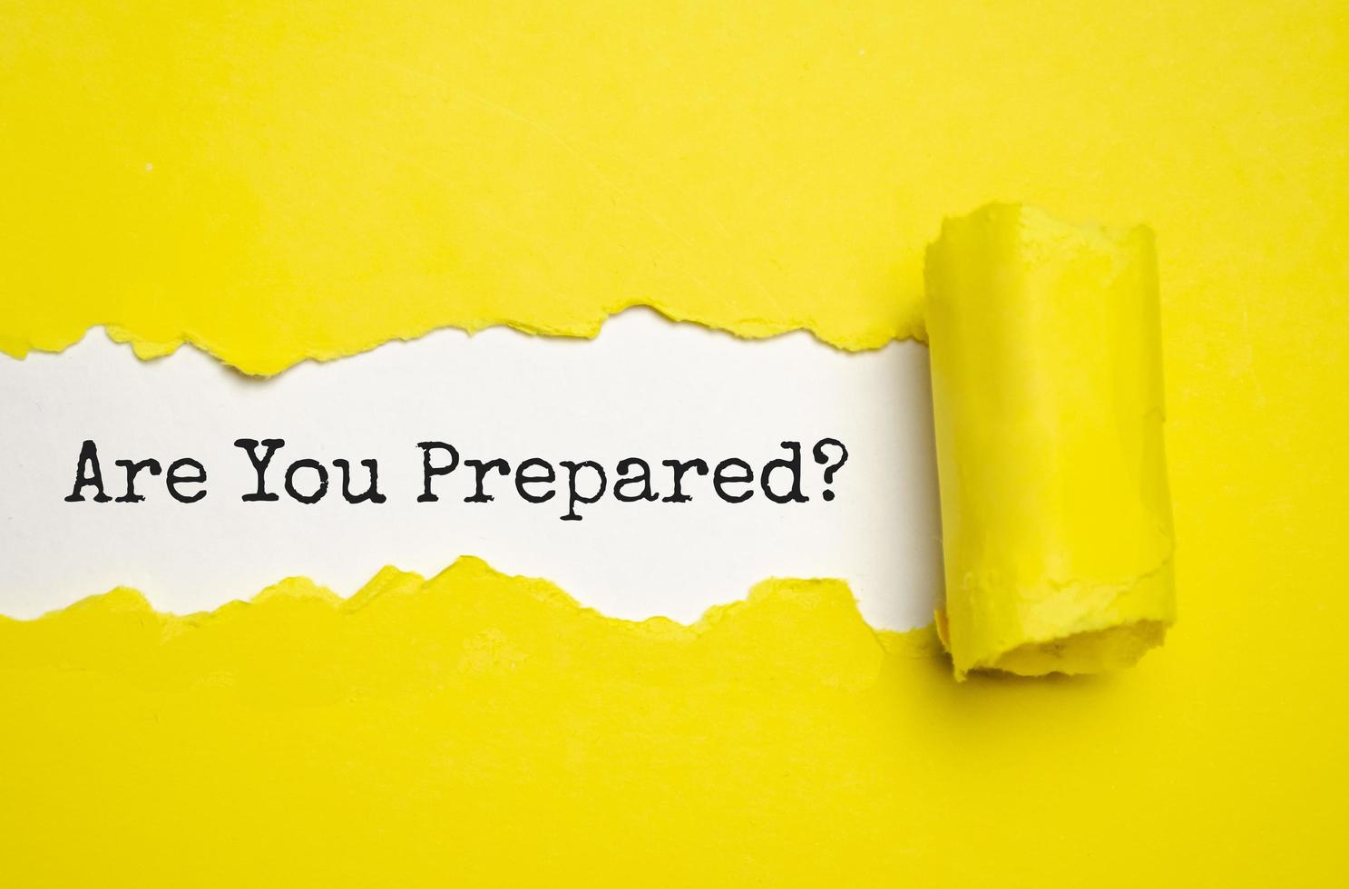 The text Are You Prepared Question appearing behind torn yellow paper photo