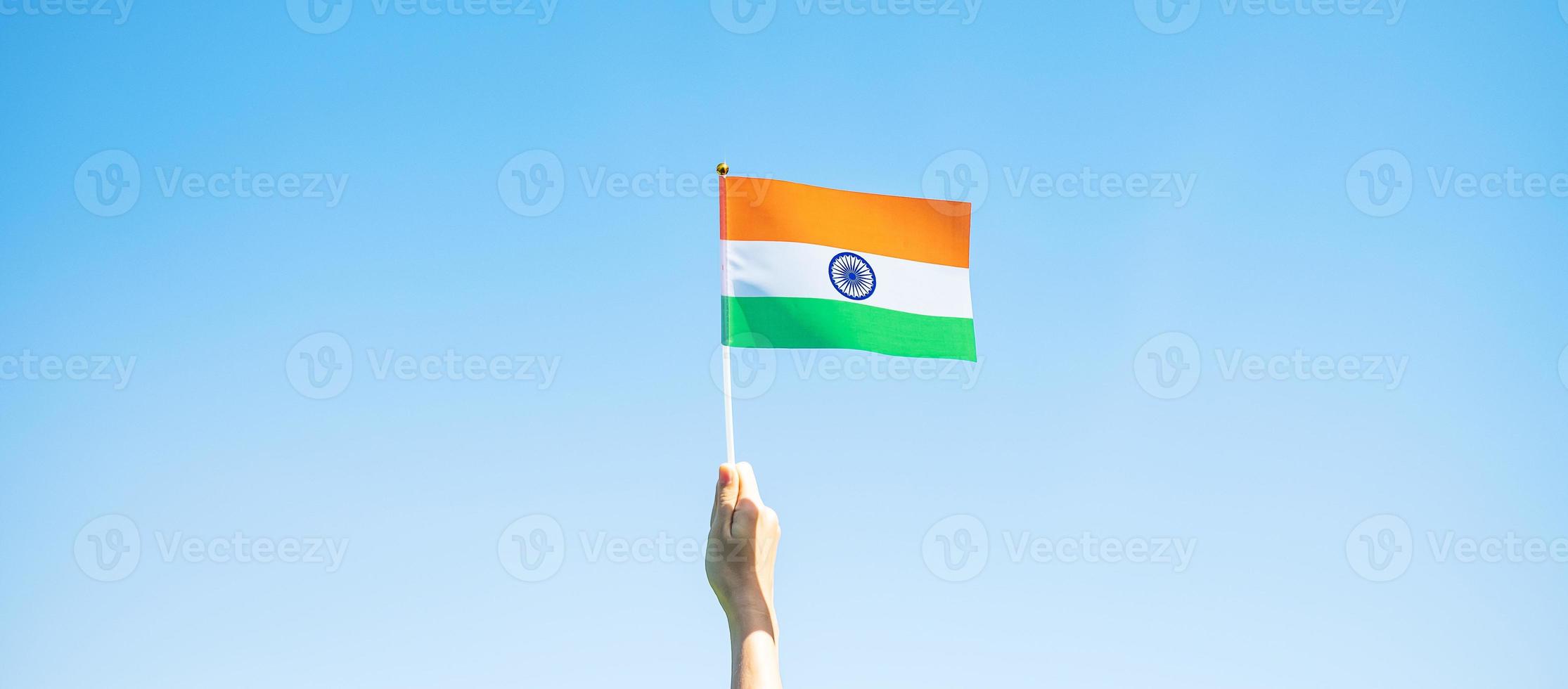 hand holding India flag on blue sky background. Holiday of India republic Day, happy Independence day and Gandhi Jayanti concepts photo