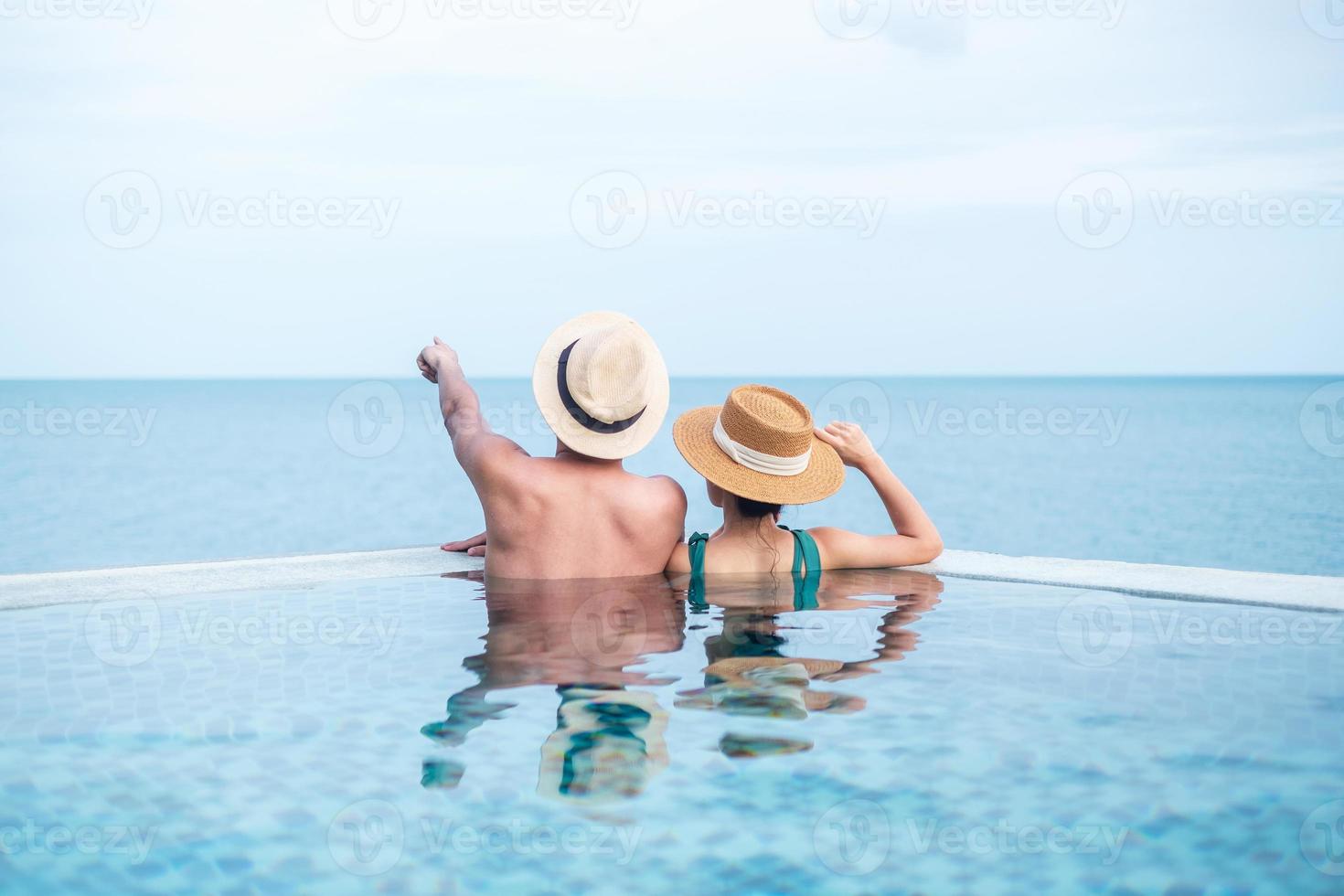 Happy couple in infinity pool at luxury hotel against ocean front., enjoy in tropical resort. Relaxing, summer,  travel, holiday, vacation , romance and weekend concept photo