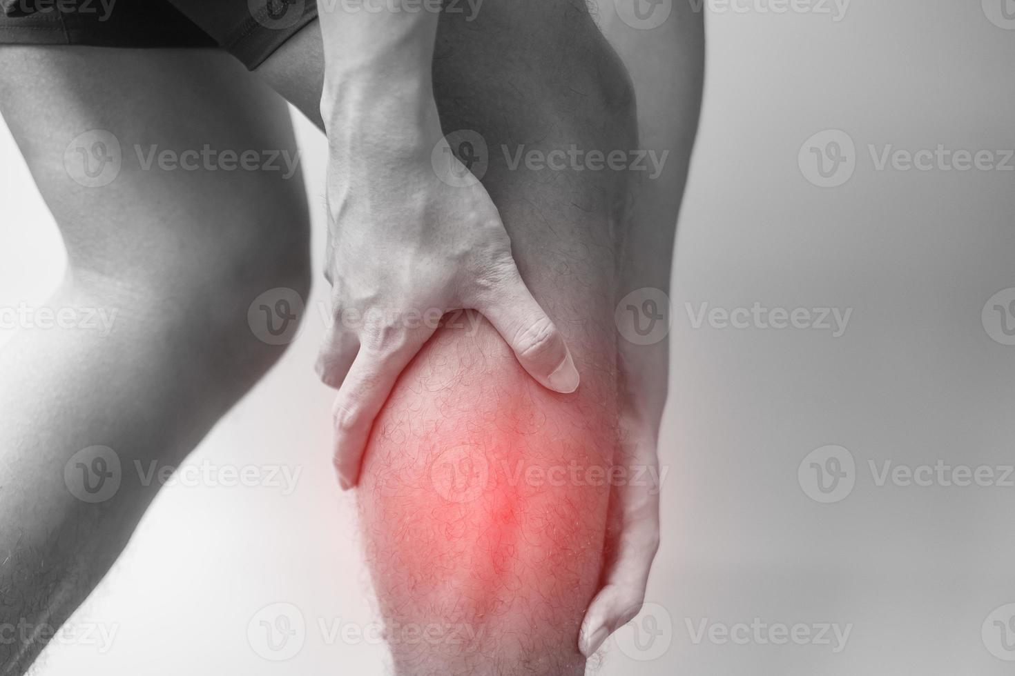 adult male with his muscle pain on gray background. Elderly man having leg ache due to Calf muscle pull. Sports injuries and medical concept photo