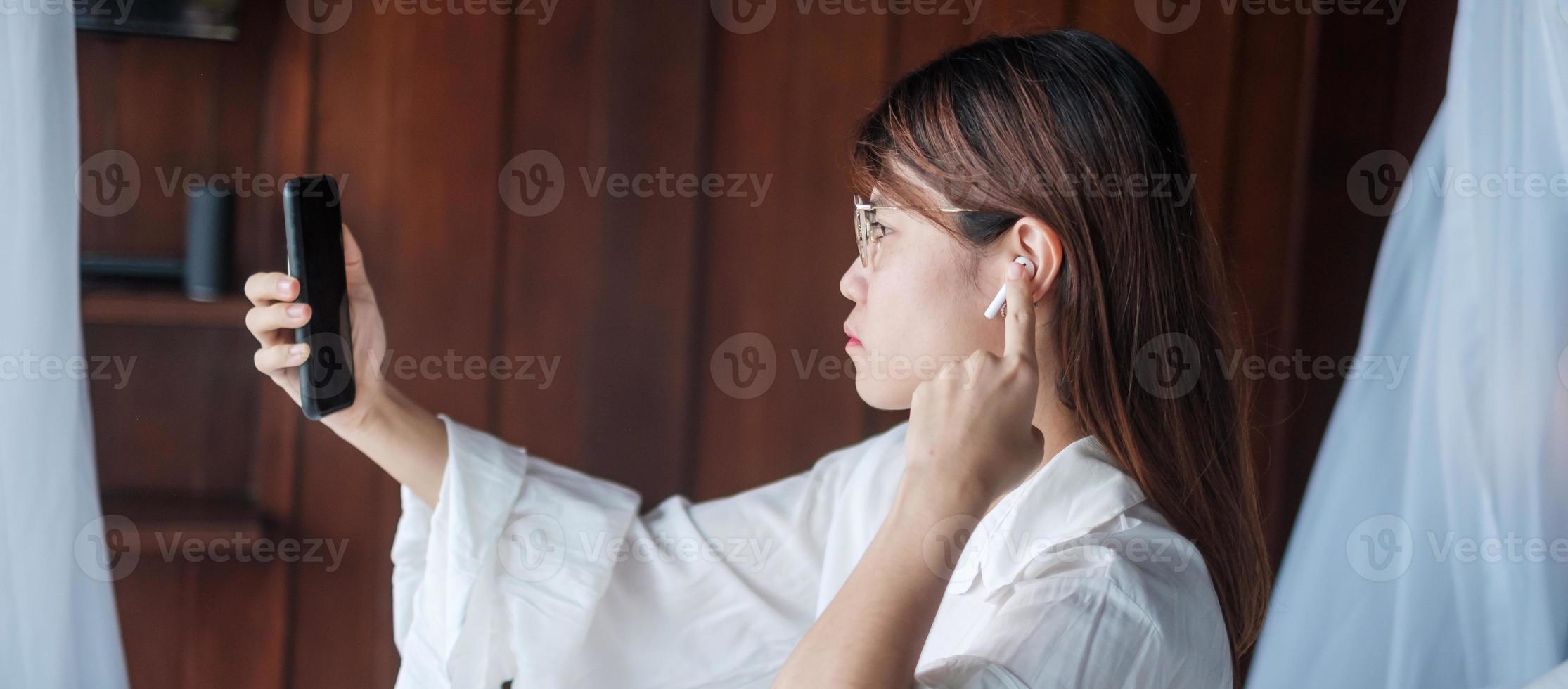 Happy woman using smart phone for video call, female meeting  online by mobile phone on bed. technology, network, work from home, lifestyle and digital communication concept photo