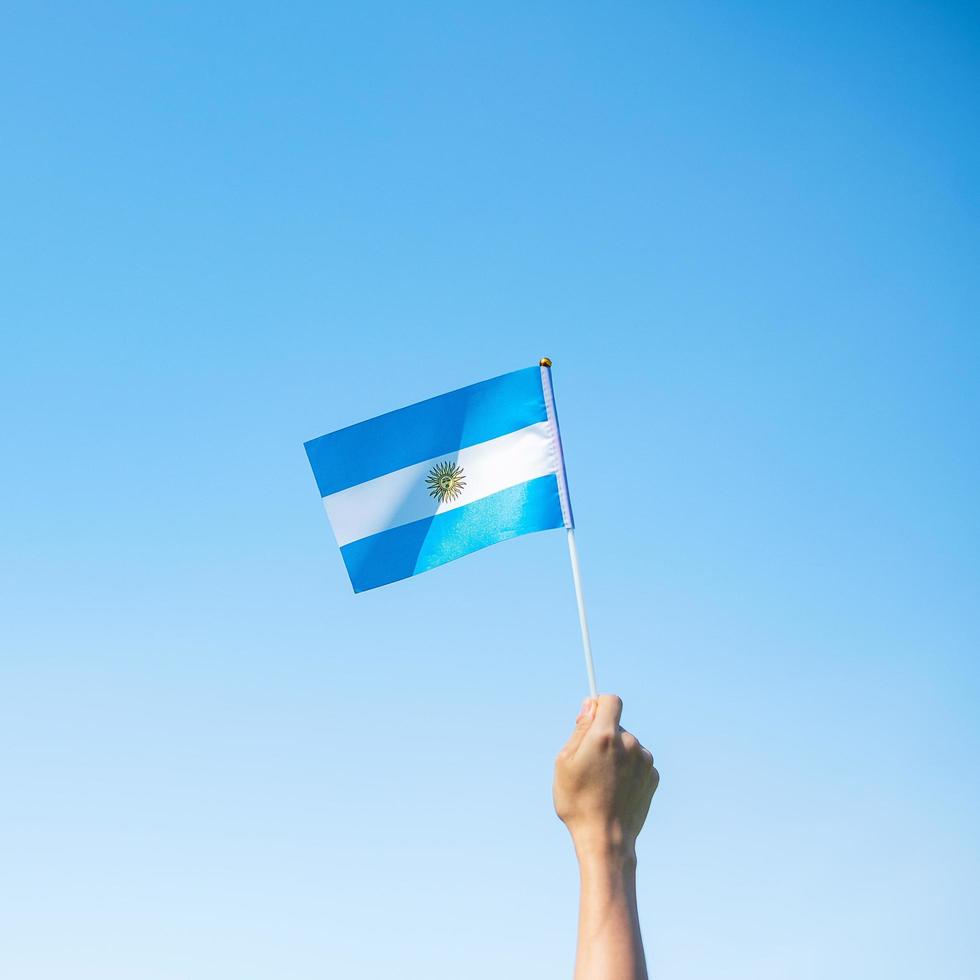 mano sosteniendo la bandera argentina en el fondo de la naturaleza. 9 de julio del día de la independencia, 25 de mayo del día de la revolución y conceptos de celebración feliz foto