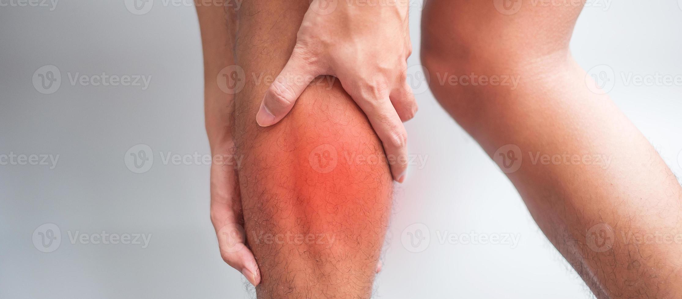 adult male with his muscle pain on gray background. Elderly man having leg ache due to Calf muscle pull. Sports injuries and medical concept photo