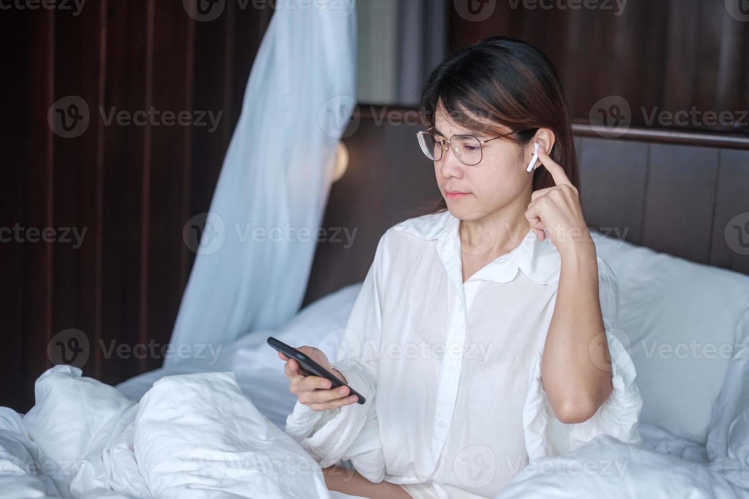 Happy woman using smart phone for video call, female meeting  online by mobile phone on bed. technology, network, work frome home, lifestyle and digital communication concept photo