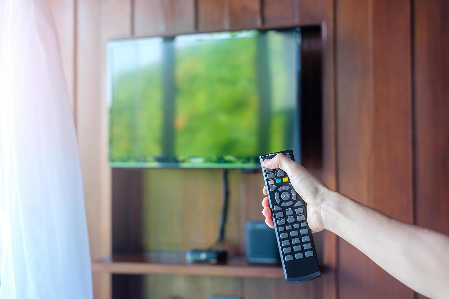 hand using remote controller for adjust Smart TV inside the modern room at home or luxury hotel photo