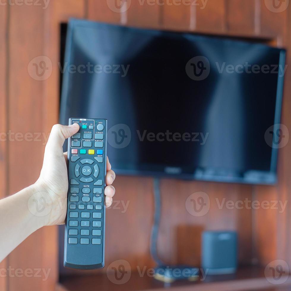 hand using remote controller for adjust Smart TV inside the modern room at home or luxury hotel photo