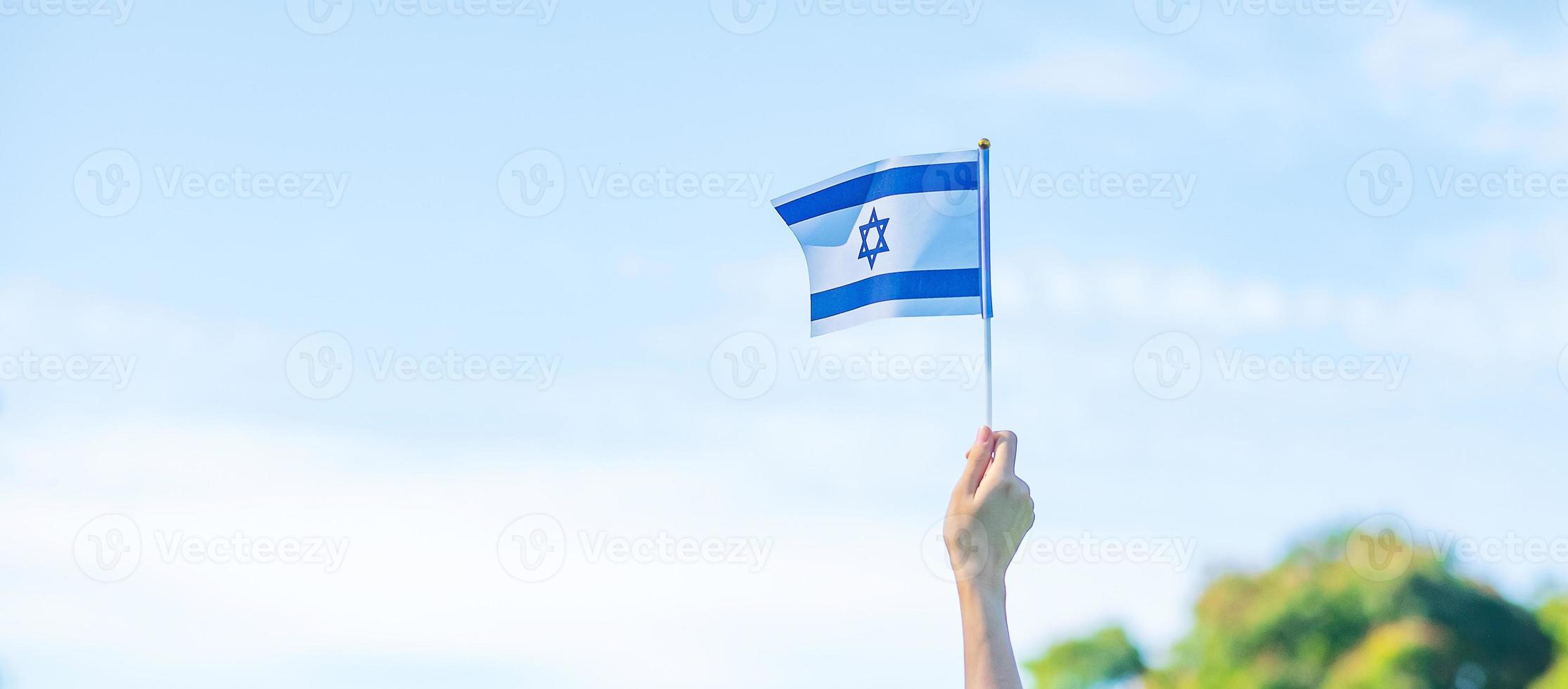 hand holding Israel flag on nature background. Israel Independence day and happy celebration concepts photo