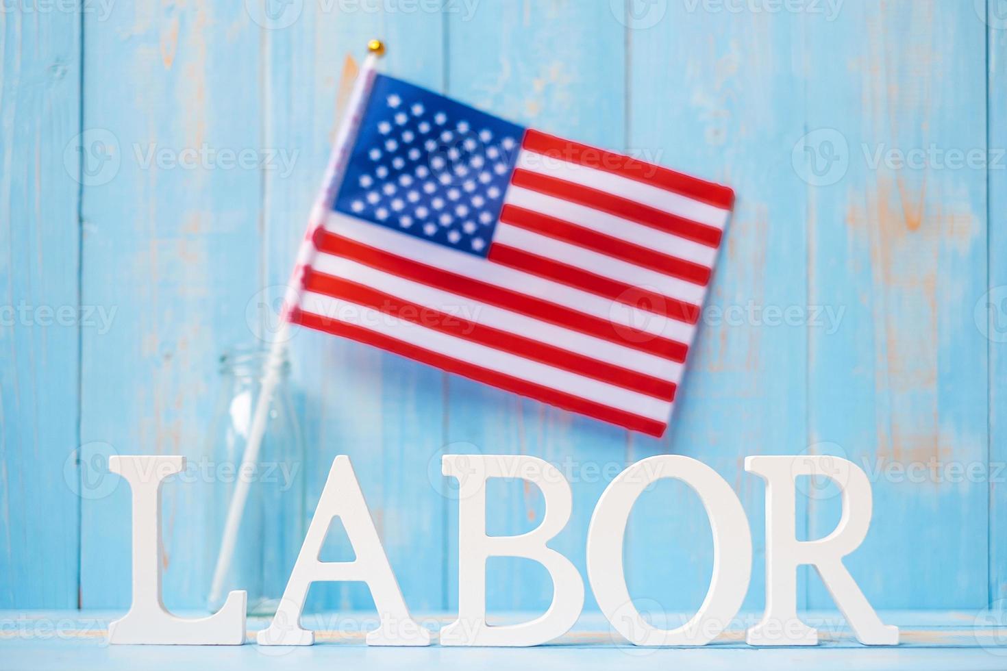 texto laboral y bandera de los estados unidos de américa sobre fondo de mesa de madera. feliz día del trabajo y conceptos de celebración navideña foto