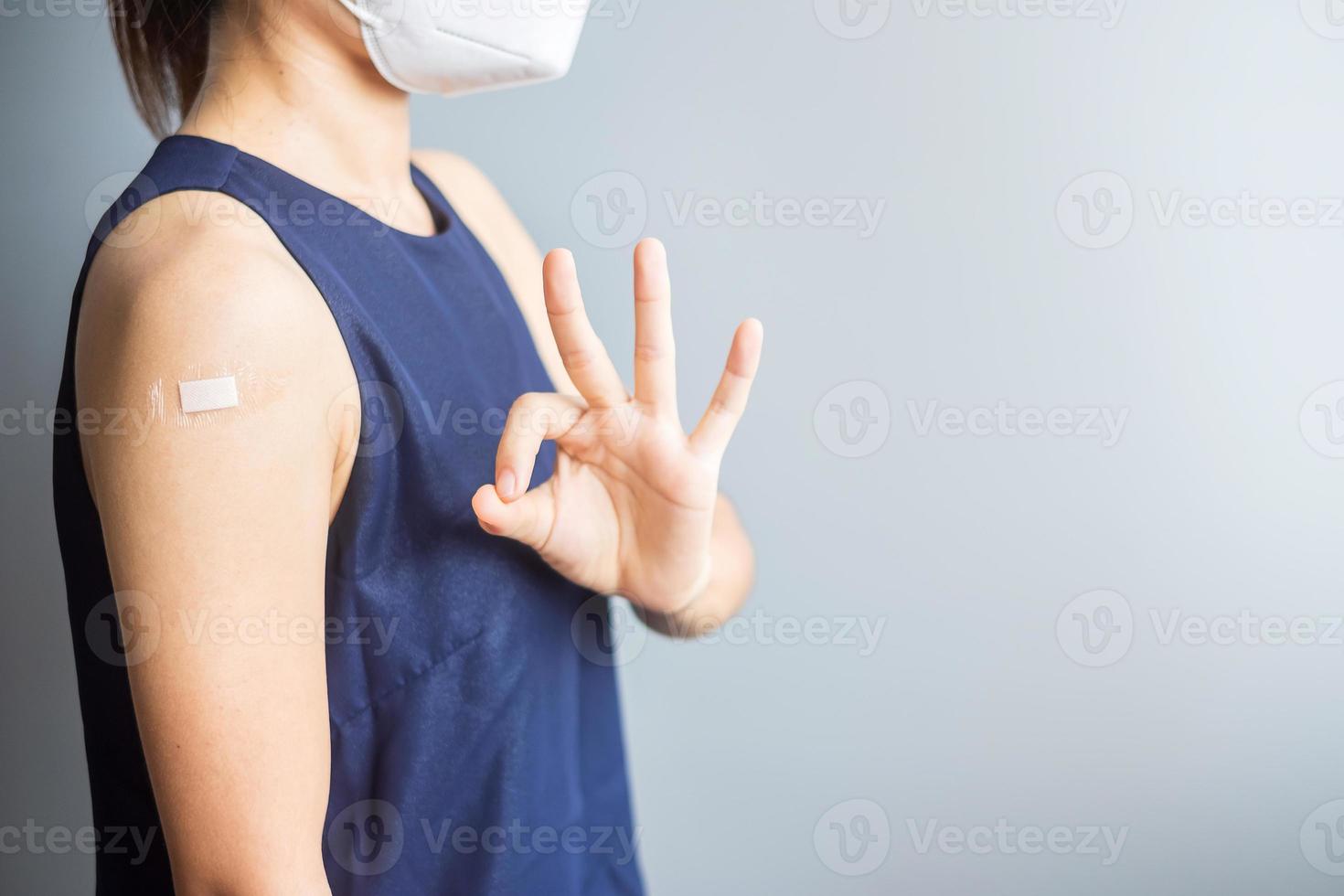 Happy woman showing OK sign with bandage after receiving covid 19 vaccine. Vaccination, herd immunity, side effect, efficiency, vaccine passport and Coronavirus pandemic photo