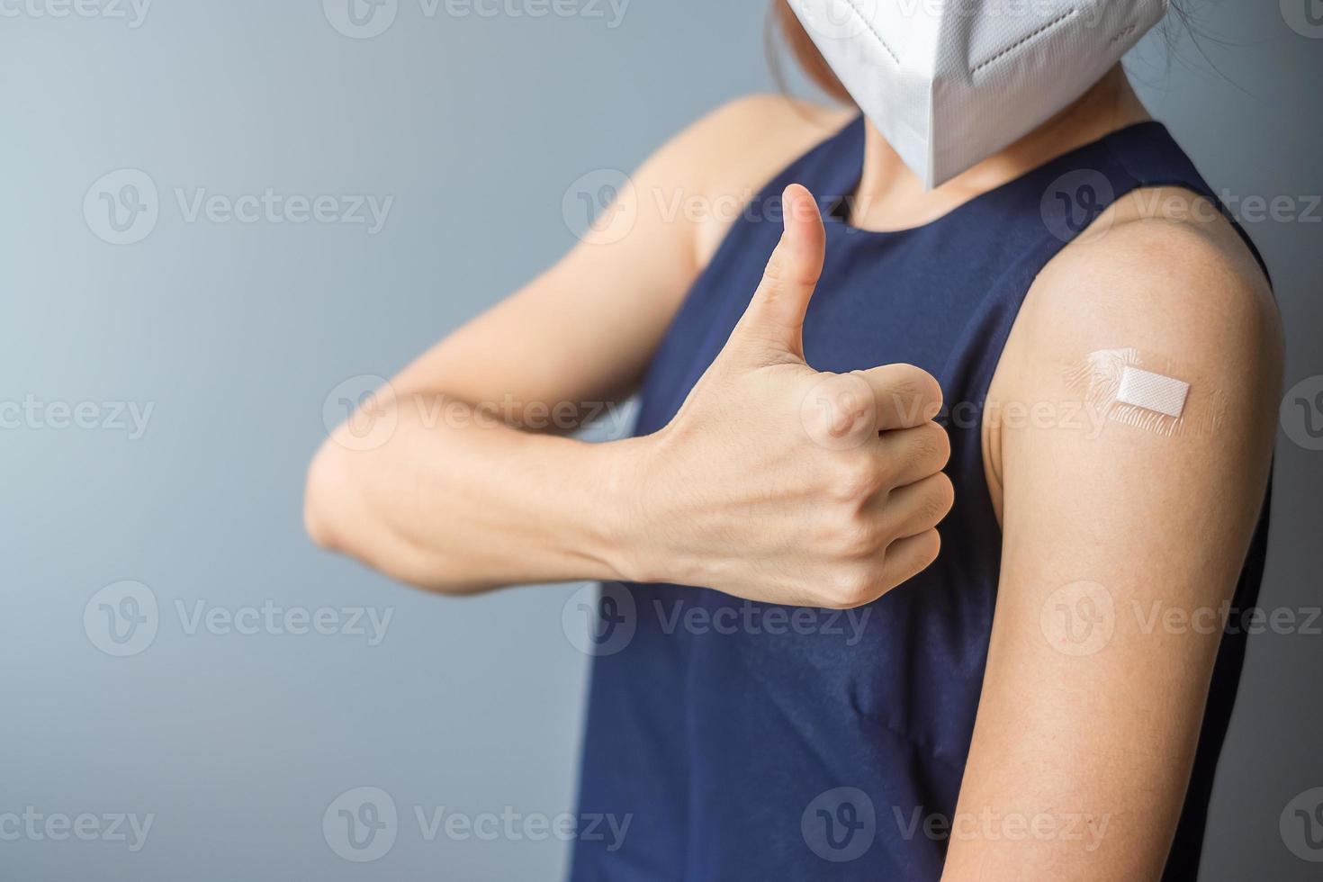Happy woman showing thumb with bandage after receiving covid 19 vaccine. Vaccination, herd immunity, side effect, efficiency, vaccine passport and Coronavirus pandemic photo