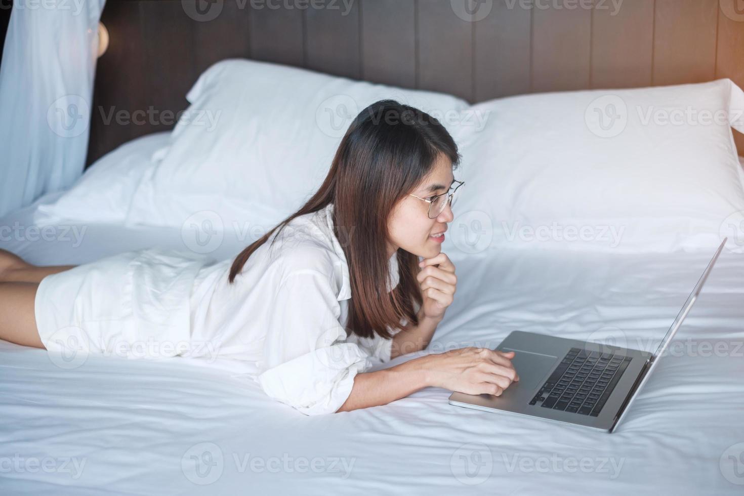 Happy woman using laptop for work, female meeting  online by computer notebook on bed. technology, network, work from home, lifestyle and digital communication concept photo