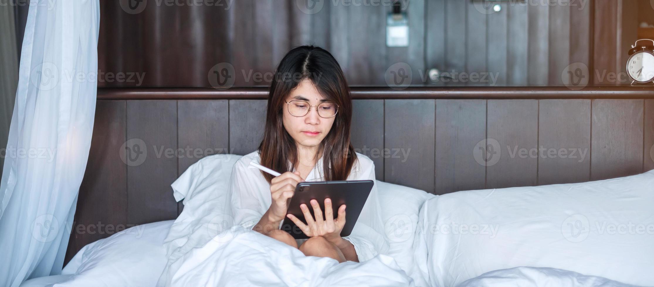 Happy woman using tablet for social media, young female watching movies on computer pad on bed at home. technology, network, online shopping, e commerce, lifestyle and digital communication concept photo