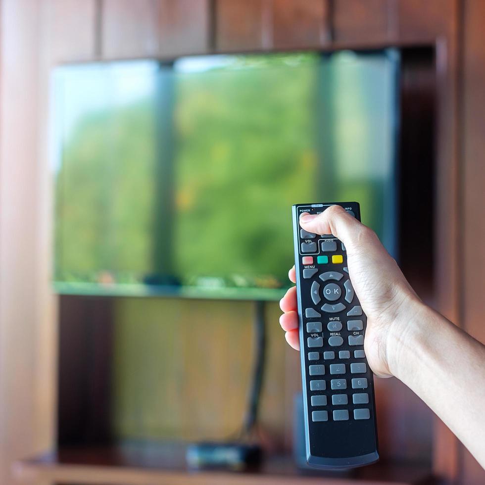hand using remote controller for adjust Smart TV inside the modern room at home or luxury hotel photo