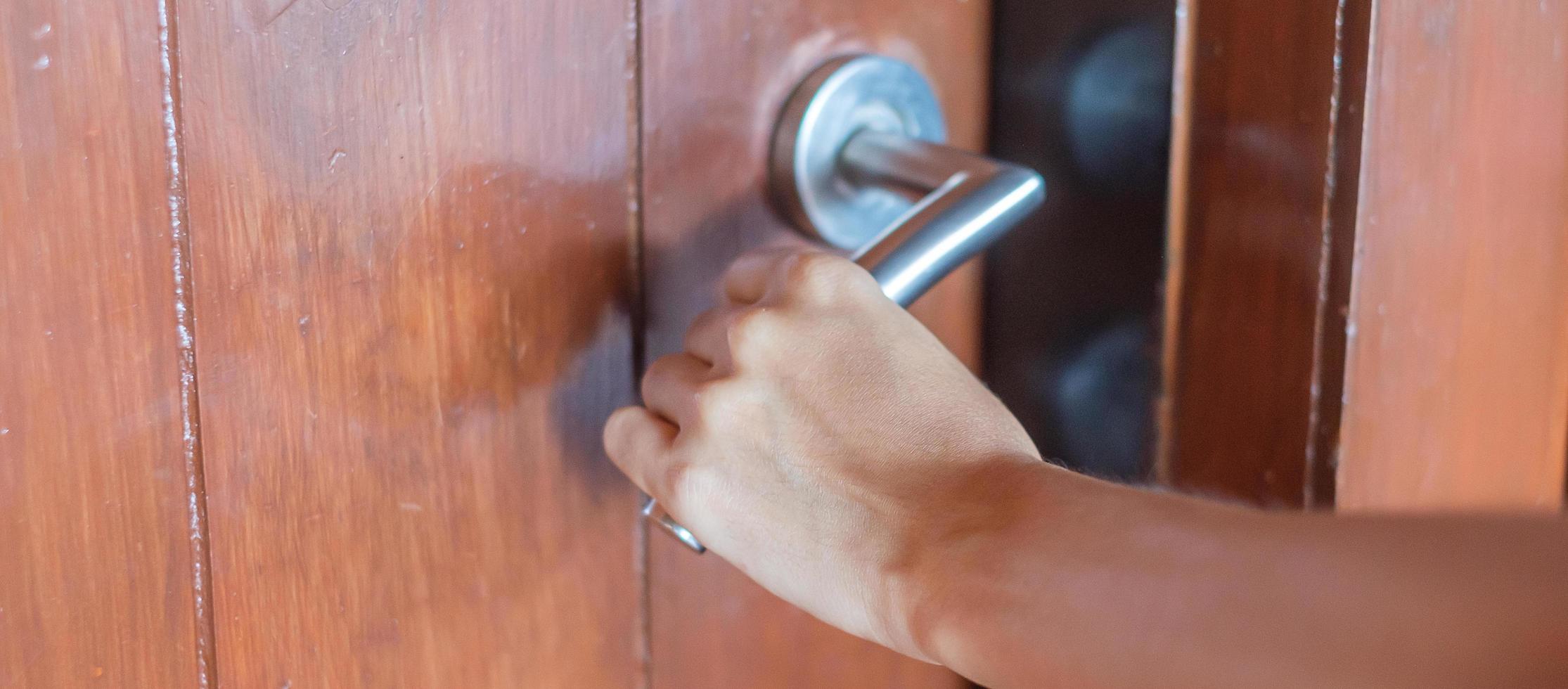Closeup man holding handle doorknob of wooden door between open or close the door photo