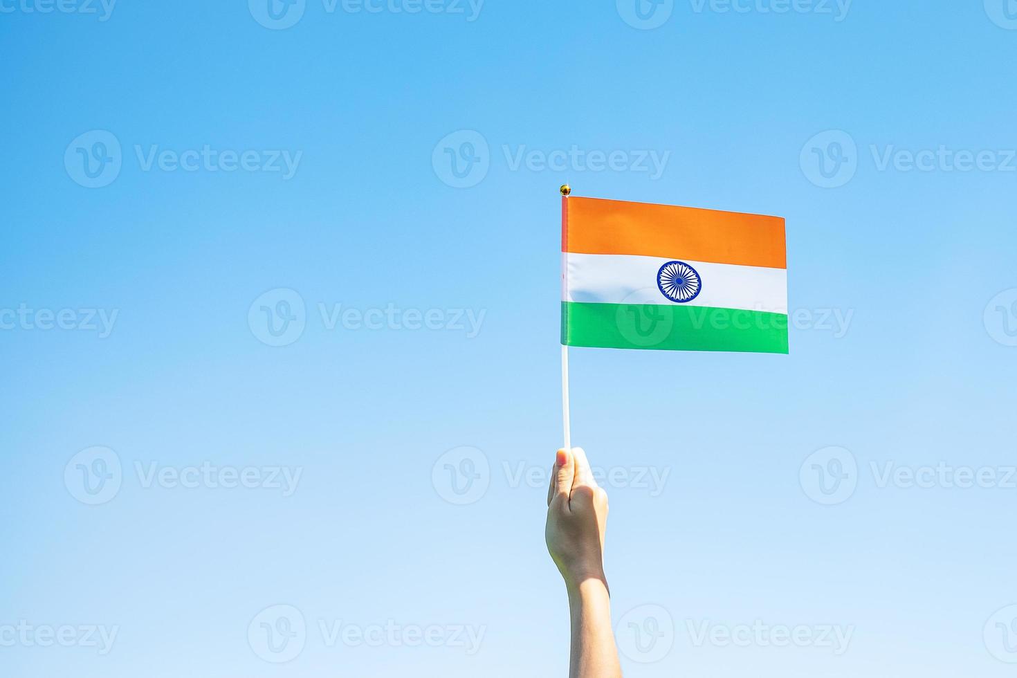 mano que sostiene la bandera india sobre fondo de cielo azul. festividad del día de la república india, feliz día de la independencia y conceptos de gandhi jayanti foto