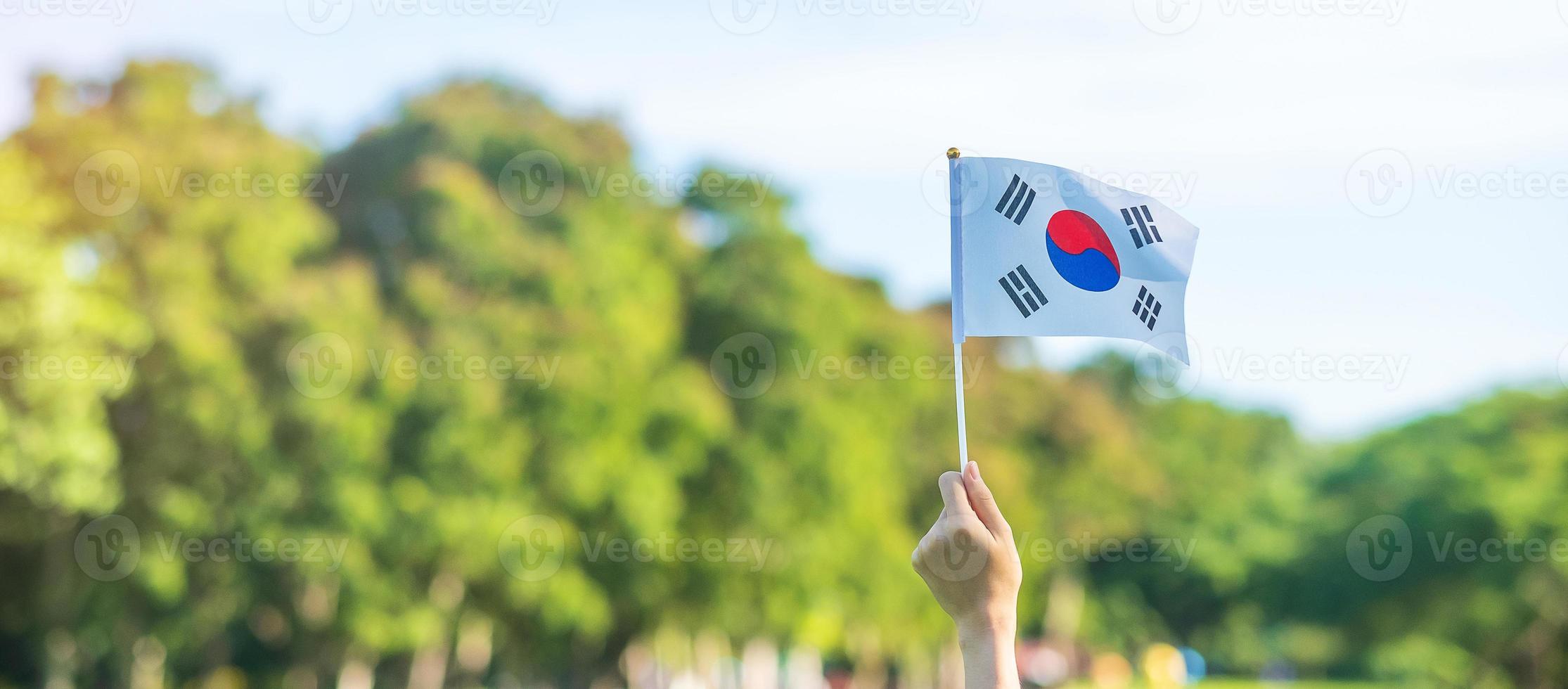 hand holding Korea flag on nature background. National Foundation, Gaecheonjeol, public Nation holiday, National Liberation Day of Korea and happy celebration concepts photo