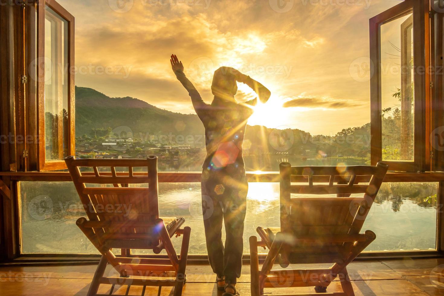 Happy young woman watching lake view at coffee shop in the morning sunrise, Ban Rak Thai village, Mae Hong Son province, Thailand. Travel concept photo