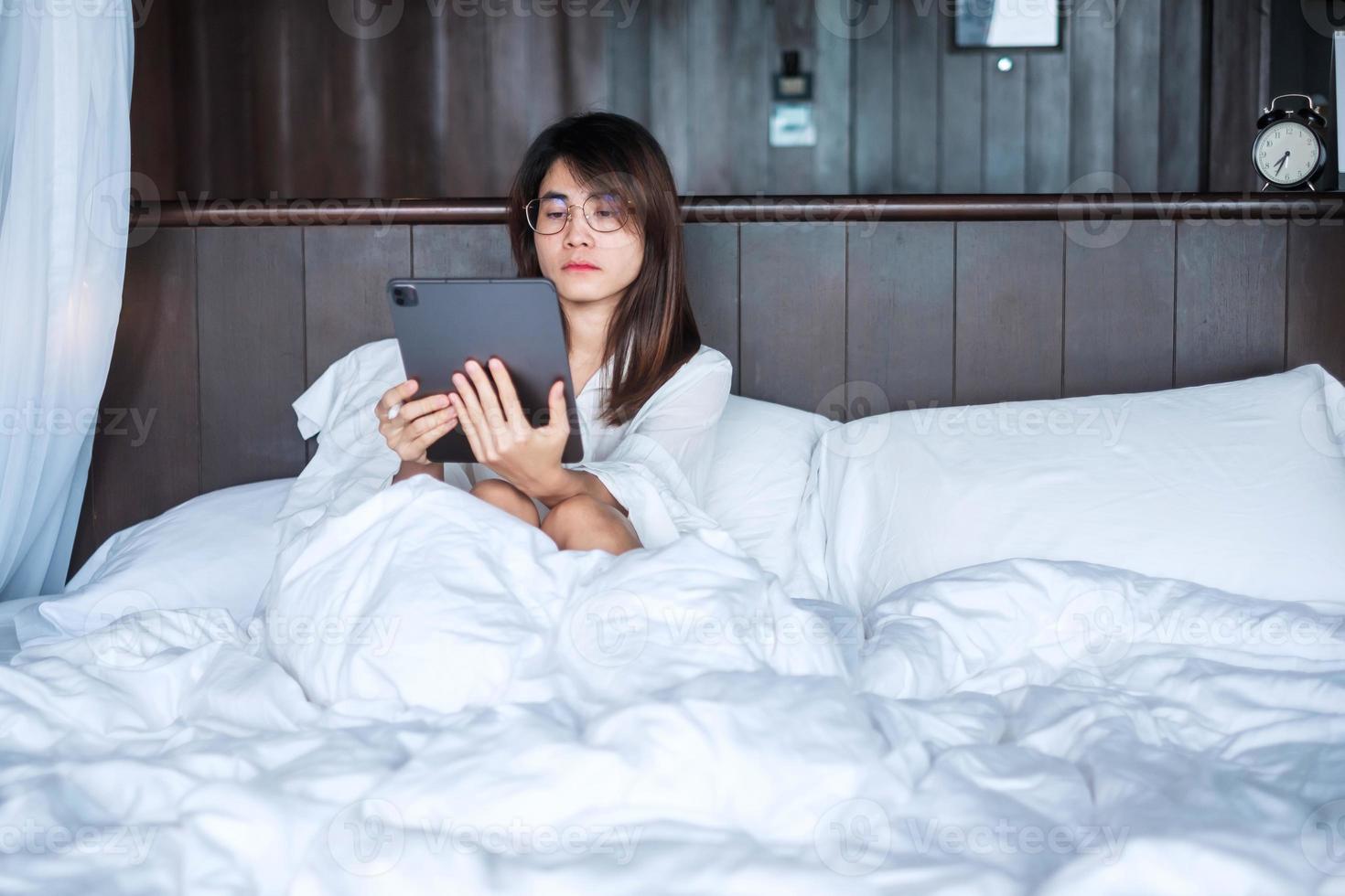 Happy woman using tablet for social media, young female watching movies on computer pad on bed at home. technology, network, online shopping, e commerce, lifestyle and digital communication concept photo