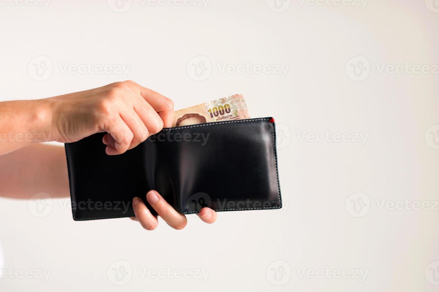 manos recogiendo dinero en baht tailandés de la billetera para pagar. foto