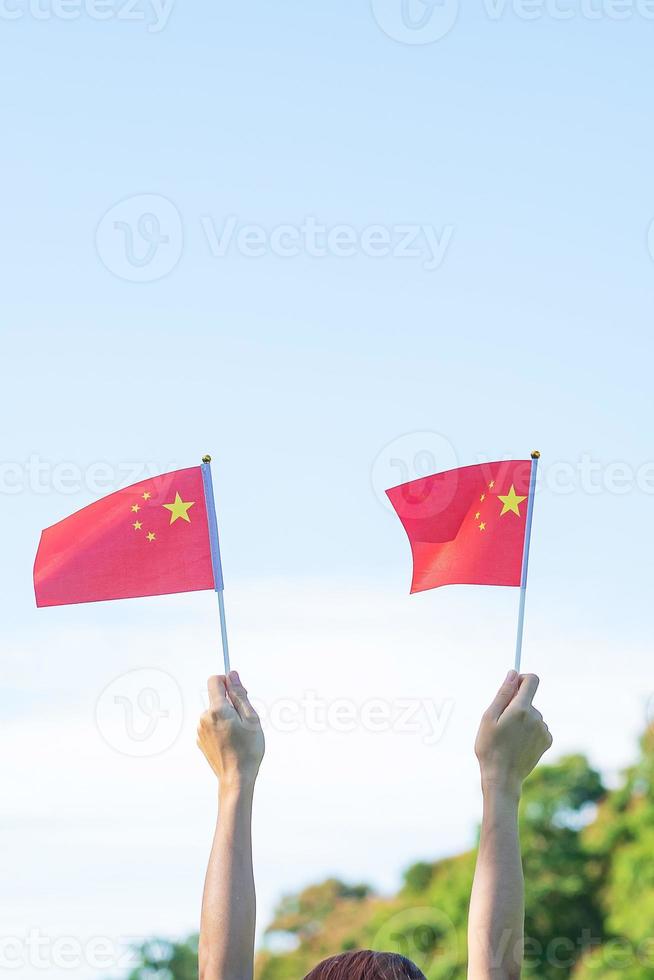 mano que sostiene la bandera china sobre fondo de cielo azul. día nacional de la república popular de china, día festivo de la nación pública y conceptos de celebración feliz foto