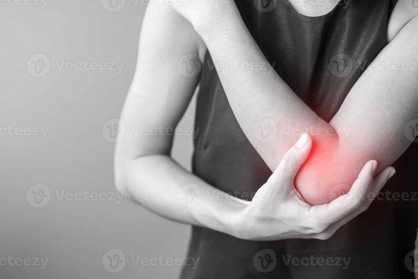 Young adult female with her muscle pain on gray background. Woman having elbow ache due to lateral epicondylitis or tennis elbow. injuries and medical concept photo