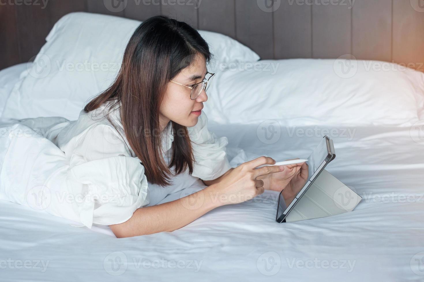 Happy woman using tablet for social media, young female watching movies on computer pad on bed at home. technology, network, online shopping, e commerce, lifestyle and digital communication concept photo
