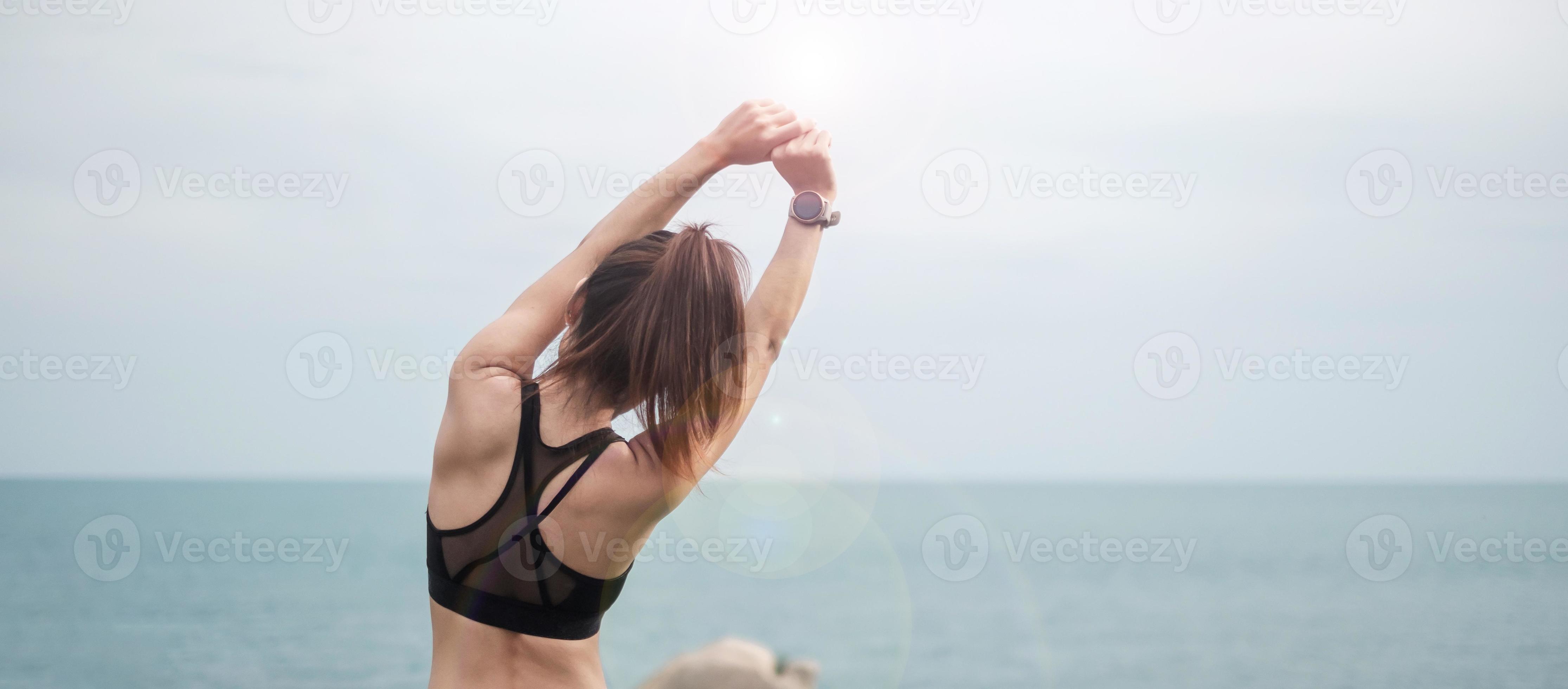 Young fitness female in sportswear stretching body against ocean view,  healthy woman exercise in morning. Workout, wellness and work life balance  concepts 9173650 Stock Photo at Vecteezy