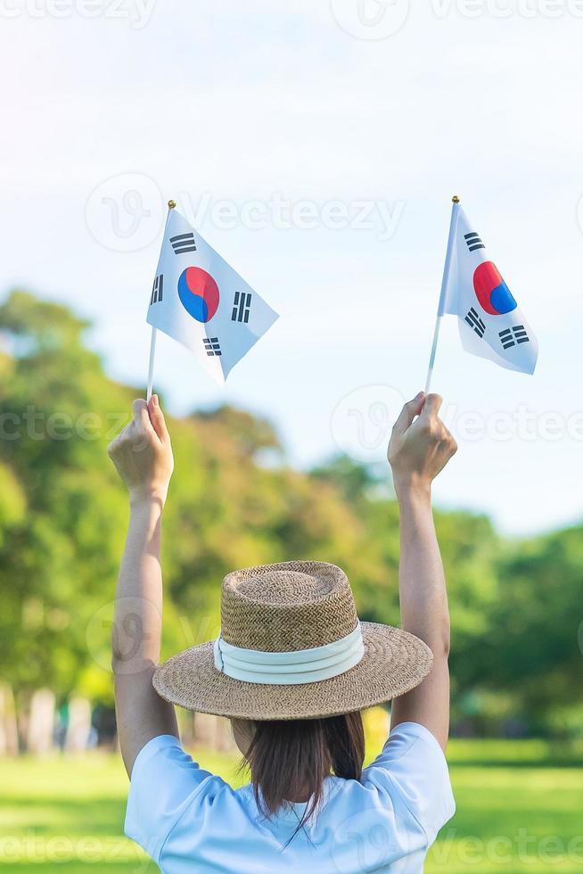 Woman hand holding Korea flag on nature background. National Foundation, Gaecheonjeol, public Nation holiday, National Liberation Day of Korea and happy celebration concepts photo