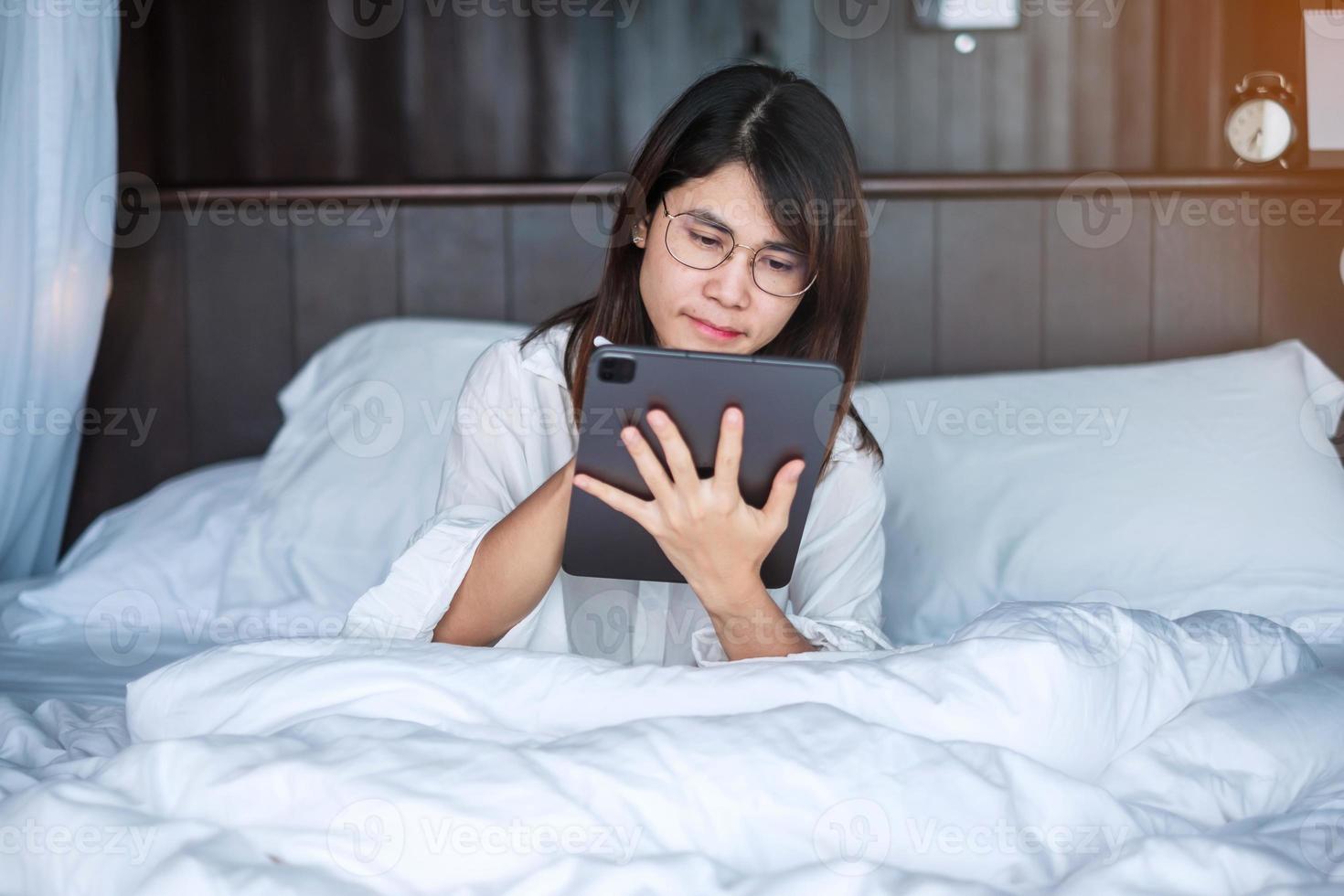 Happy woman using tablet for social media, young female watching movies on computer pad on bed at home. technology, network, online shopping, e commerce, lifestyle and digital communication concept photo