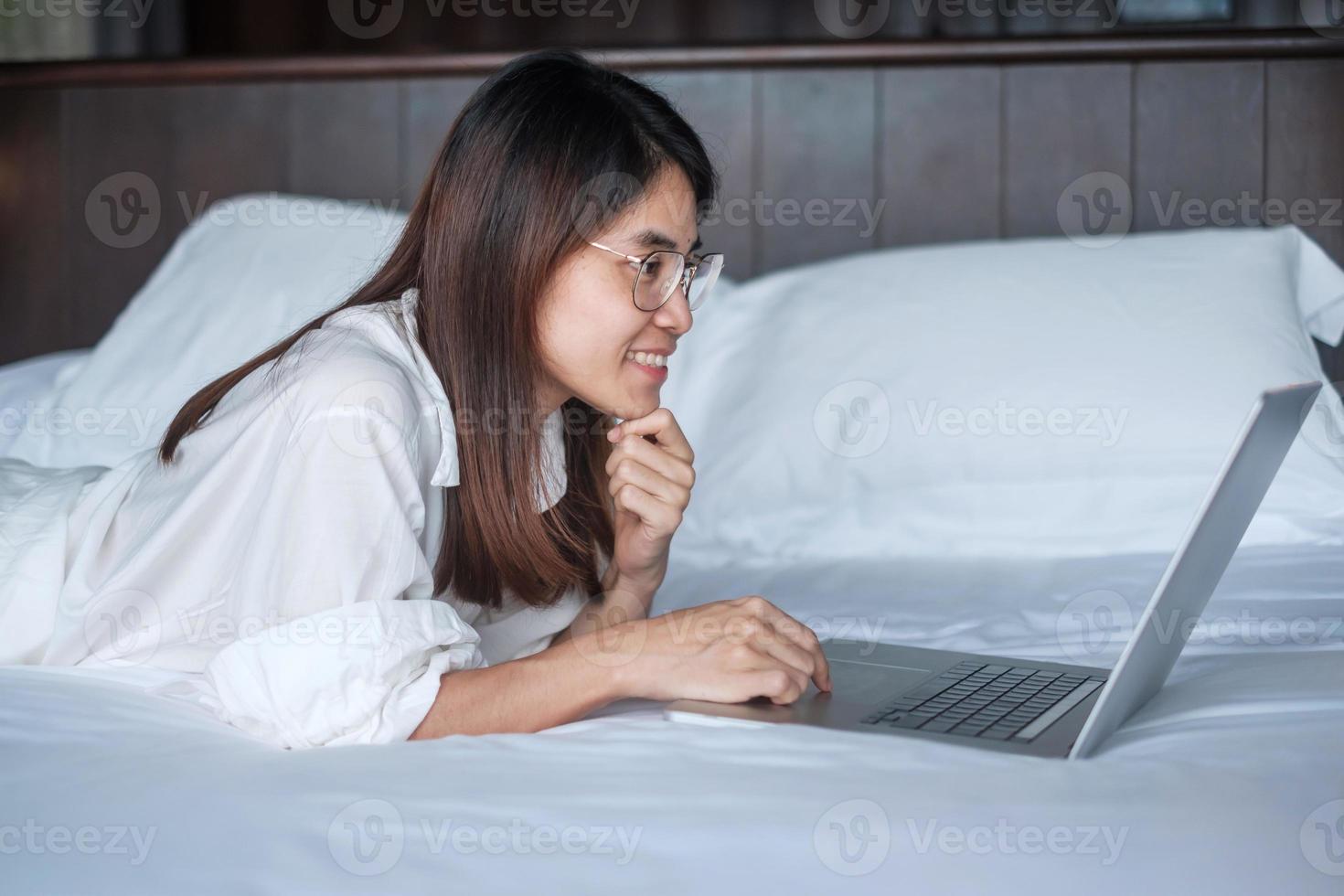 Happy woman using laptop for work, female meeting  online by computer notebook on bed. technology, network, work from home, lifestyle and digital communication concept photo