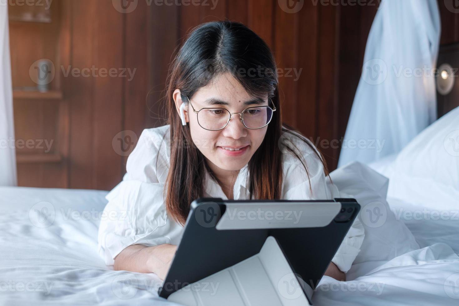 Happy woman using tablet for social media, young female watching movies on computer pad on bed at home. technology, network, online shopping, e commerce, lifestyle and digital communication concept photo