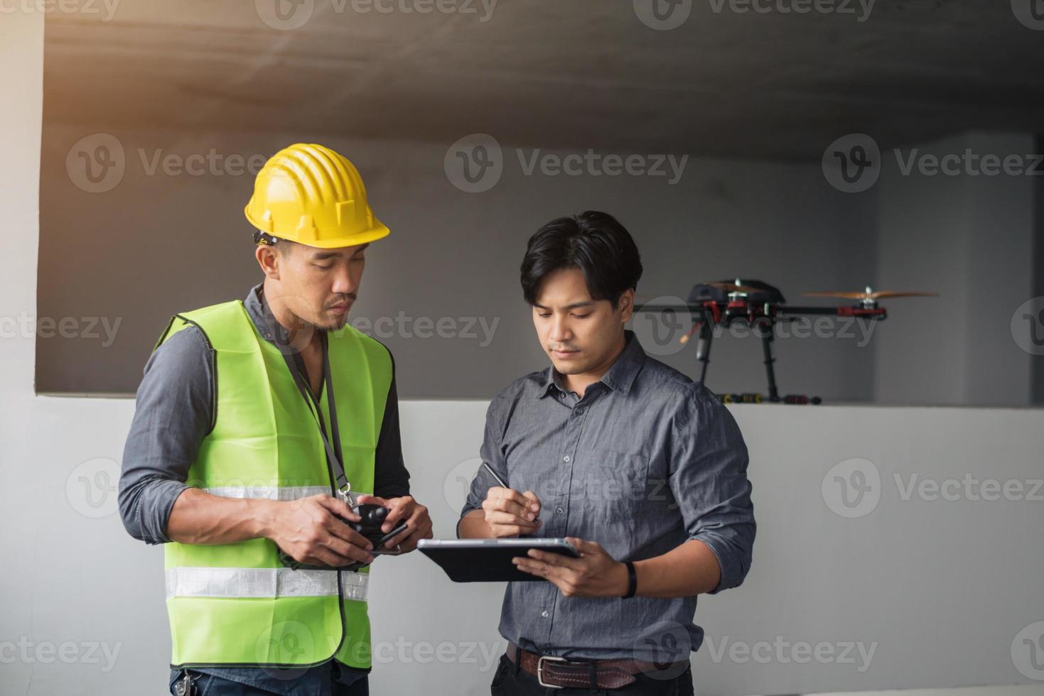 trabajadores de la construcción discutiendo sobre el plan de trabajo en el sitio de construcción. trabajador de la construcción hablando sobre el plan de trabajo con drones en el sitio. foto