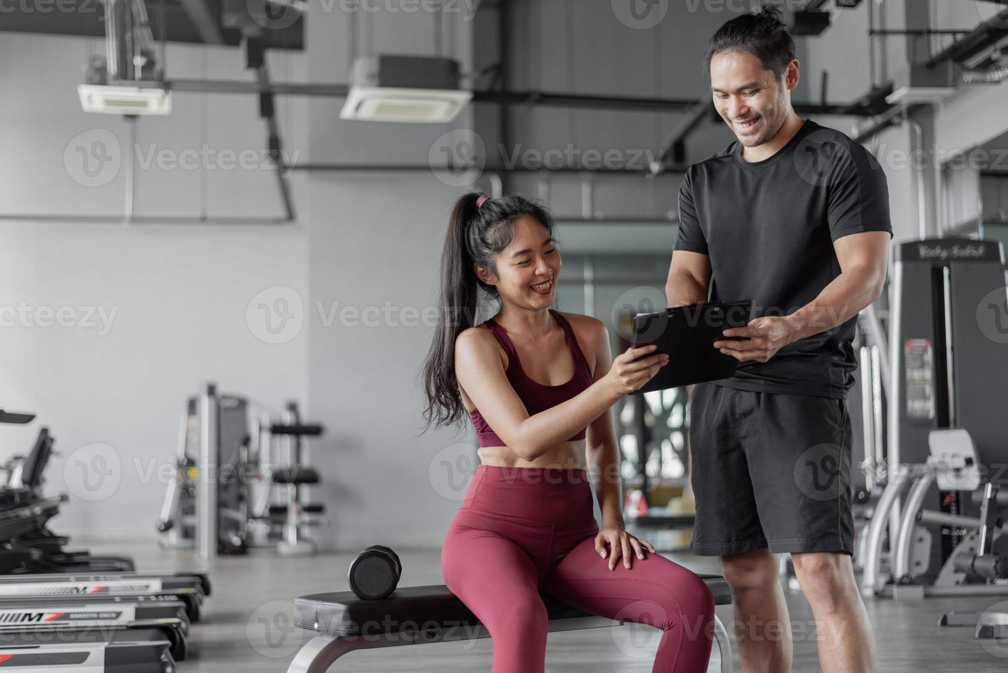 Asian woman exercise with personal trainer in gym. Personal trainer showing and talking about