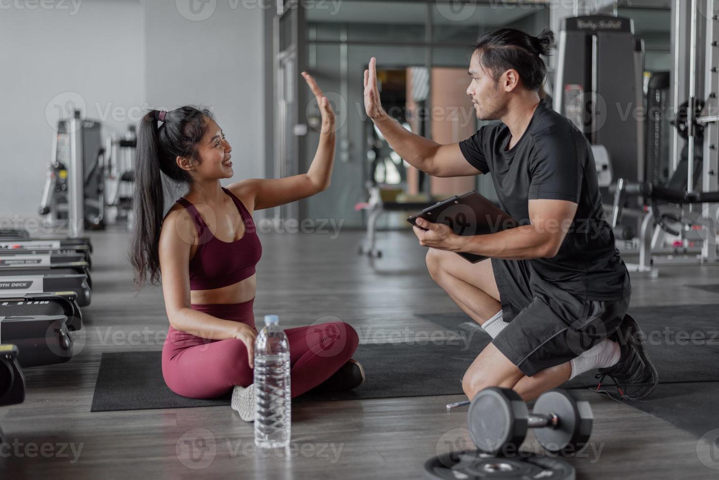 Asian woman exercise with personal trainer in gym. Healthy woman give me five with personal trainer. photo