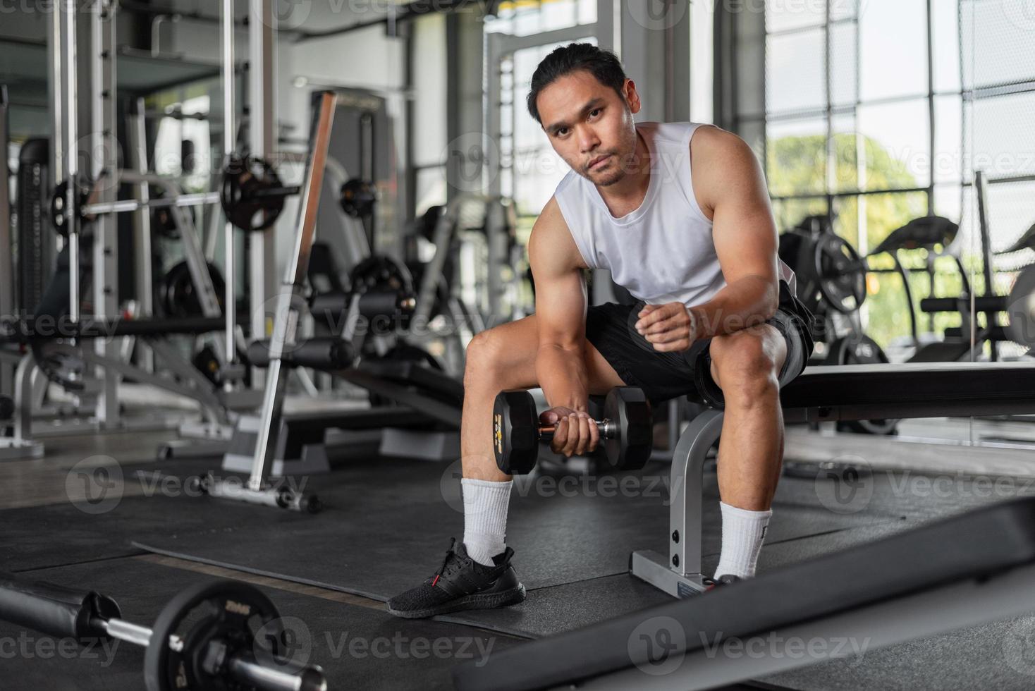Asian man exercises in fitness. Fit man doing bicep curl exercises in gym. photo