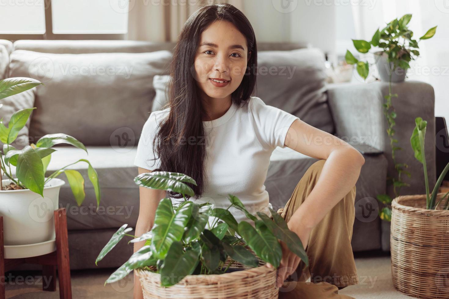 mujer feliz sentada con sus plantas en casa. mujer asiática jardinería en casa, jardinería doméstica. foto