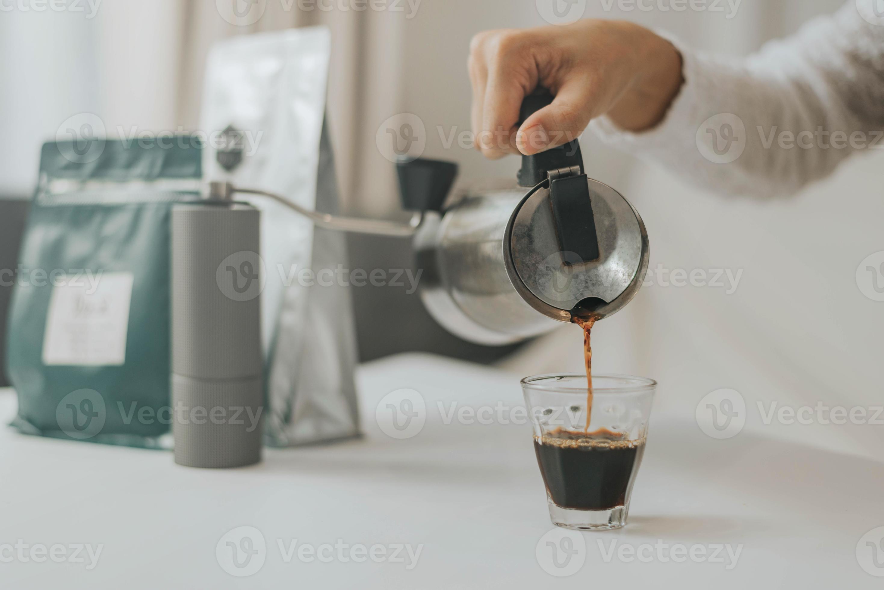 Sirviendo café en una taza desde una cafetera con granos de café Stock  Photo