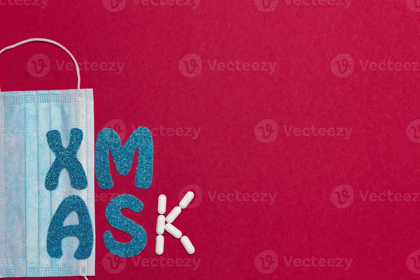 Medical protective mask on red background. Inscription Xmas. Christmas and New Year card, banner, advertising concept. Top view photo, minimalism, copy space. Medical flatly. photo