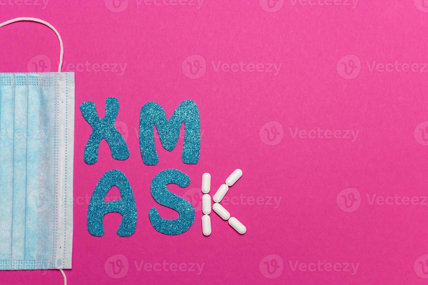 Medical protective mask on pink background. Inscription Xmas. Christmas and New Year card, banner, advertising concept. Top view photo, minimalism, copy space. Medical flatly. High quality photo