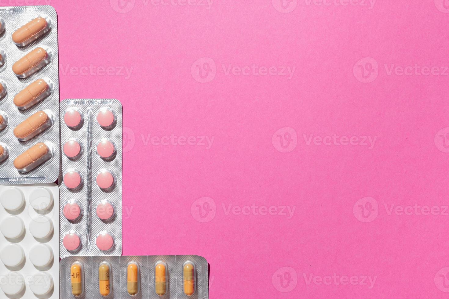 Different medicines, tablets, pills in blister pack, medications drugs on pink background. Close-up photo, copy space, top view. photo