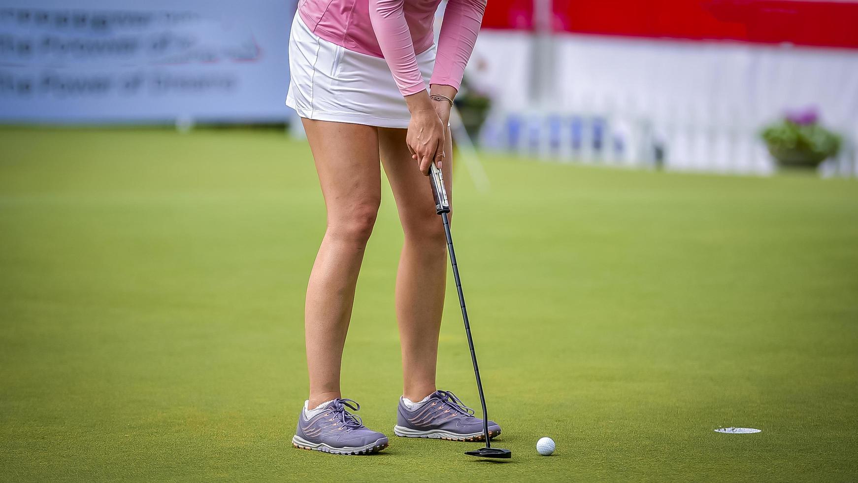 golfista empujando la pelota de golf blanca al hoyo en el campo de golf en el juego de competencia de golf, rayos de luz solar y fondo borroso foto